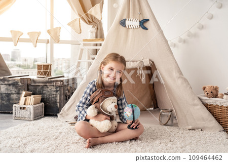 Little girl with teddy bear and globe sitting in wigwam settled in playroom Little girl with teddy bear and globe sitting in wigwam settled in playroom 109464462