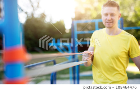 Sportsman exercising with elastic rubber band, close up view on band 109464476