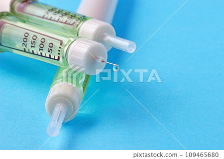 Insulin syringe pen with a drop of insulin at the end of the needle on a blue background Insulin syringe pen with a drop of insulin at the end of the needle on a blue background 109465680