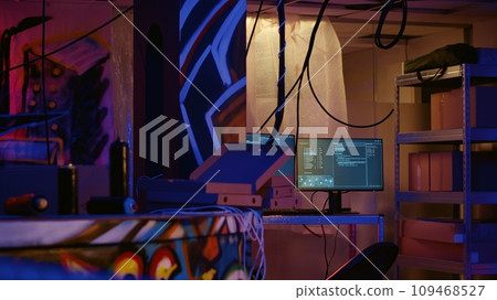 Zoom in on advanced technology computers left open running code in empty neon lit basement with graffiti drawings painted on walls. High tech equipment used by hackers in underground warehouse Zoom in on advanced technology computers left open running code in empty neon lit basement with graffiti drawings painted on walls. High tech equipment used by hackers in underground warehouse 109468527