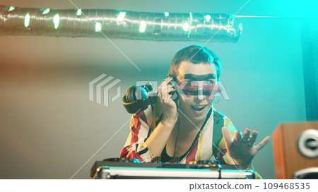 Happy artist working as dj with electric turntables, mixing electronic bass music with audio instruments. DJ performer playing party music on stage at nightclub, joclifestyle. Handheld shot. 109468535