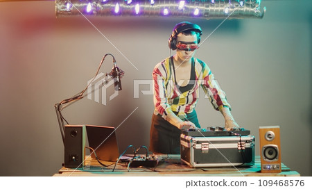 Disc jockey gives thumbs down on stage after mixing stereo sounds at turntables, showing dislike and disapproval sign while she uses mixer keys. Expressing rejection and disagreement. Tripod shot. Disc jockey gives thumbs down on stage after mixing stereo sounds at turntables, showing dislike and disapproval sign while she uses mixer keys. Expressing rejection and disagreement. Tripod shot. 109468576