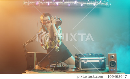 Funky dj artist mixing tunes on electronic turntables, using buttons and bass control key to mix techno sounds. Disc jockey performing with mixer at nightclub party event. Tripod shot. Funky dj artist mixing tunes on electronic turntables, using buttons and bass control key to mix techno sounds. Disc jockey performing with mixer at nightclub party event. Tripod shot. 109468647