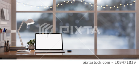 Home office workspace with a white-screen laptop on a wooden desk against the window on winter day. 109471839