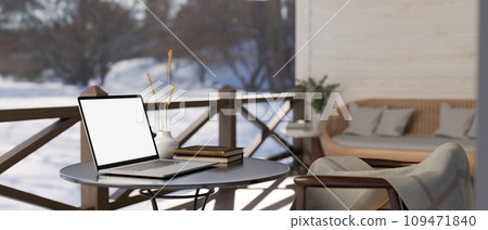 A white-screen laptop computer on a table on a cosy home porch or balcony in a winter day. A white-screen laptop computer on a table on a cosy home porch or balcony in a winter day. 109471840
