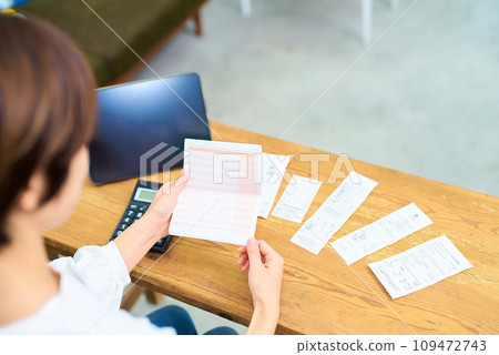 一個女人看著銀行存摺的後視圖 一個女人看著銀行存摺的後視圖 109472743