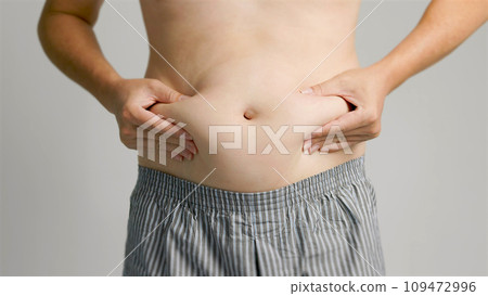 close up of man hand pinching excessive belly fat 109472996