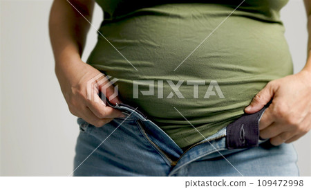 Fat  woman zipping up trousers, excess belly fat, unhealthy lifestyle 109472998