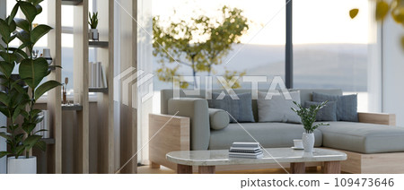 A modern living room with a cosy couch, a coffee table, a partition wall, and houseplants. A modern living room with a cosy couch, a coffee table, a partition wall, and houseplants. 109473646