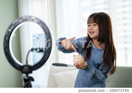 A cute young Asian girl is reviewing her toy while live streaming on her social media. 109473784