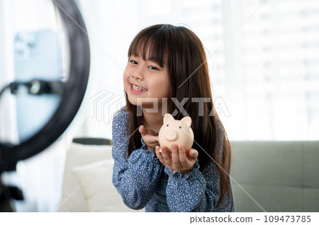 A cute young Asian girl is reviewing her toy while live streaming on her social media. 109473785