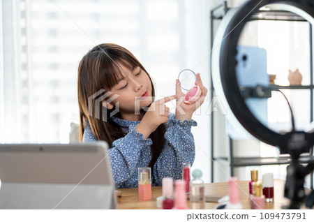 A pretty young Asian girl kid influencer is recording her makeup video to review kid cosmetics. 109473791