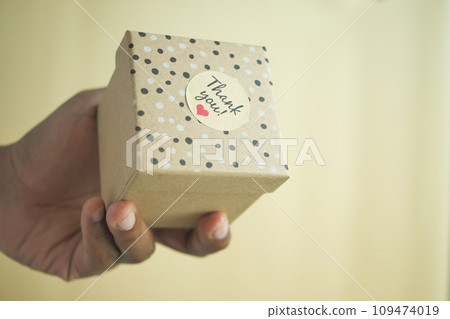 hand putting a thank you sticker on a gift box hand putting a thank you sticker on a gift box 109474019