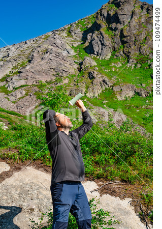 Rejuvenating Break: Traveler Enjoying Cold Water in the Mountain Wilderness on a Hot Sunny Day 109474499