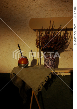 Mate calabash with bombilla. Healthy infused drink, classic Yerba mate tea on a chair on a cozy patio, backyard. Hot beverage on a terrace. Traditional Latin America cuisine. Useful drink still life. Mate calabash with bombilla. Healthy infused drink, classic Yerba mate tea on a chair on a cozy patio, backyard. Hot beverage on a terrace. Traditional Latin America cuisine. Useful drink still life. 109474819
