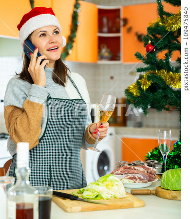 Young woman in xmas hat with phone and glass of champagne Young woman in xmas hat with phone and glass of champagne 109475840