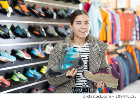 Girl examine compare item of winter comfortable tracking shoes Girl examine compare item of winter comfortable tracking shoes 109476155