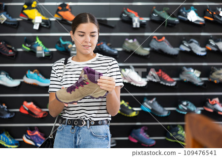 Girl examine compare item of autumn comfortable tracking shoes Girl examine compare item of autumn comfortable tracking shoes 109476541
