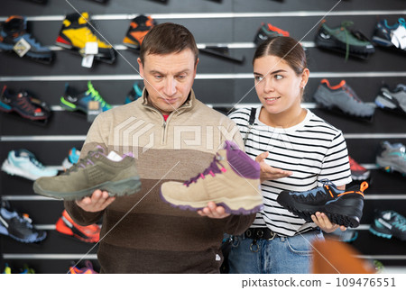 Man with daughter chooses autumn trekking cross-shoes 109476551