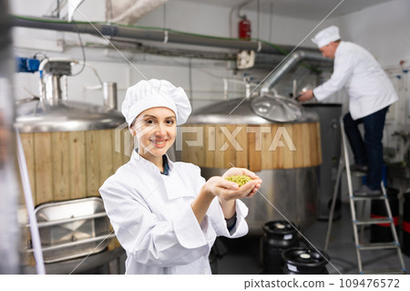 Smiling woman brewer holding bunch of hop pellets 109476572