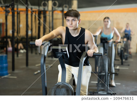 Young guy doing cardio workout on exercise bike in gym 109476631