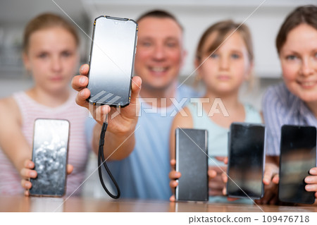 Different smartphones with blank screens in hands of cheerful family Different smartphones with blank screens in hands of cheerful family 109476718