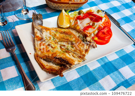 Grilled gilthead bream with pesto, vegetable salad and slice of lemon 109476722