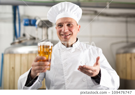 Cheerful man brewer presenting glass of beer 109476747