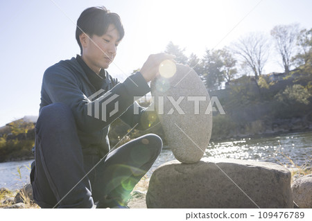 一個人在河岸上做岩石平衡 109476789