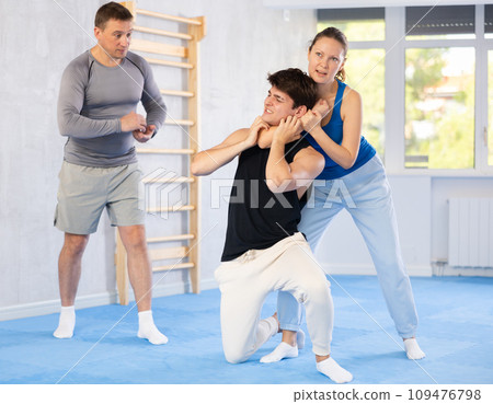 Guy and woman train to perform defense of strangling opponent, while learning self-defense Guy and woman train to perform defense of strangling opponent, while learning self-defense 109476798