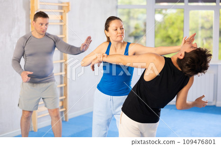 Woman practices blows to head of her attacking man during self-defense training under the guidance of trainer Woman practices blows to head of her attacking man during self-defense training under the guidance of trainer 109476801