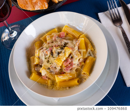 Tortiglioni pasta carbonara with cheese sauce and cured pork Tortiglioni pasta carbonara with cheese sauce and cured pork 109476868