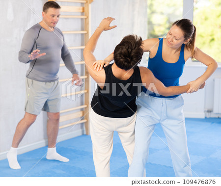 Guy and woman train to perform defense of strangling opponent, while learning self-defense Guy and woman train to perform defense of strangling opponent, while learning self-defense 109476876