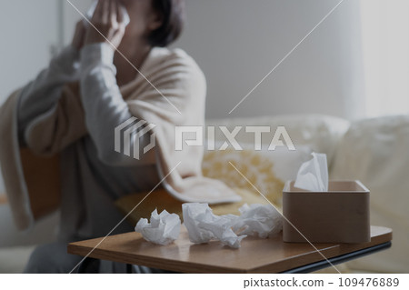 A woman who has a cold and blows her nose A woman who has a cold and blows her nose 109476889