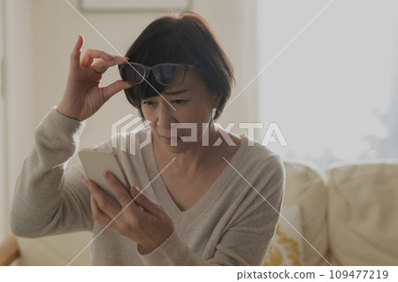 A woman with presbyopia who has difficulty seeing her smartphone A woman with presbyopia who has difficulty seeing her smartphone 109477219