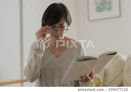 A woman who has difficulty reading books due to presbyopia A woman who has difficulty reading books due to presbyopia 109477220