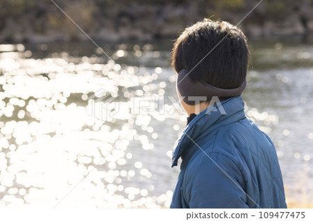 Rear view of a man wearing cold weather and looking at the river Rear view of a man wearing cold weather and looking at the river 109477475