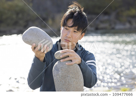 一名男子嘗試在強風中保持岩石平衡 一名男子嘗試在強風中保持岩石平衡 109477666
