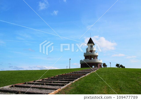 Observation tower at the end of the stairs with a summer blue sky, white clouds, and contrails in the background 109477789