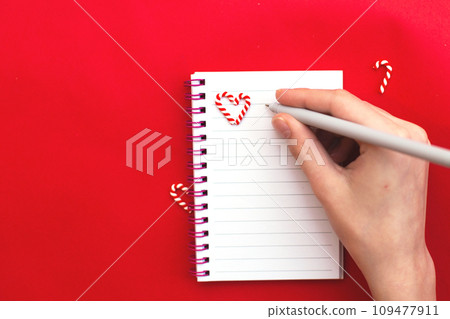 Top view of child hand with holding pen on white paper blank notebook and writing wish list. 109477911