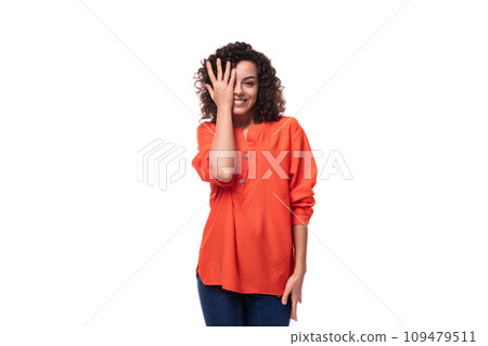 young curly brunette woman dressed in an orange blouse on a white background 109479511