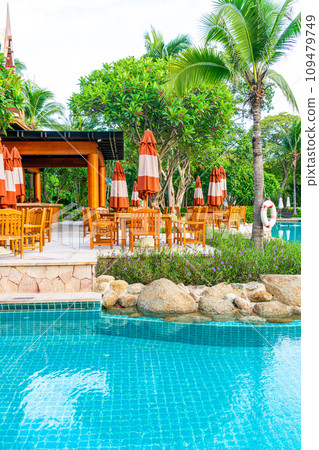 Umbrella with chair and table around swimming pool 109479749