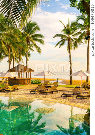 Beautiful luxury umbrella and chair around outdoor swimming pool in hotel and resort with coconut palm tree on sunset  or sunrise sky 109479819