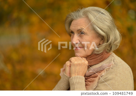 Senior woman walking in the park in autumn. Senior woman walking in the park in autumn. 109481749