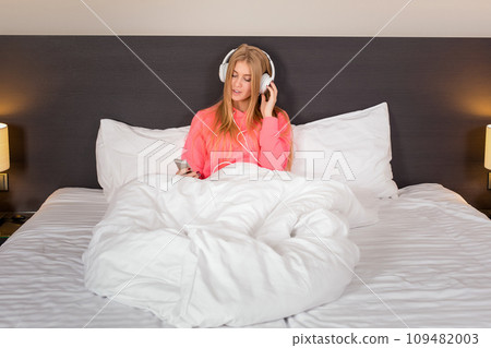 Young women listening to the music from smartphone on bed 109482003