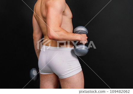 Man with a pumped-up body with dumbbells in his hands white panties exercise 109482062
