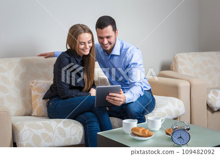Young man and woman on the couch with electronic tablet 109482092