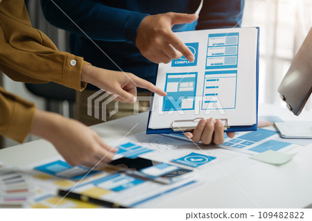 designer brainstorming about mobile app interface wireframe design with customer breif and color code at office. designer brainstorming about mobile app interface wireframe design with customer breif and color code at office. 109482822