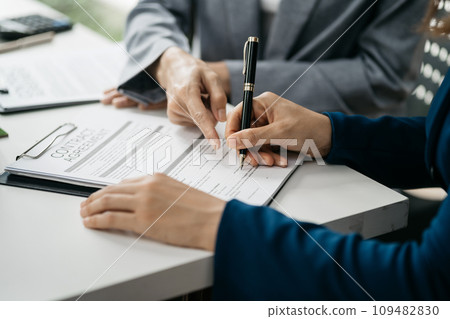 Real estate broker agent presenting and consult to customer to decision making sign insurance form agreement, home model, concerning mortgage loan offer in office. 109482830