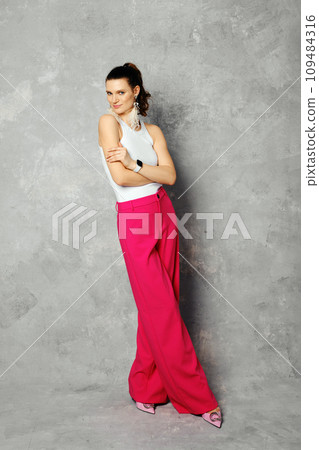 Tricky woman in loose trousers and tank top posing on abstract background 109484316